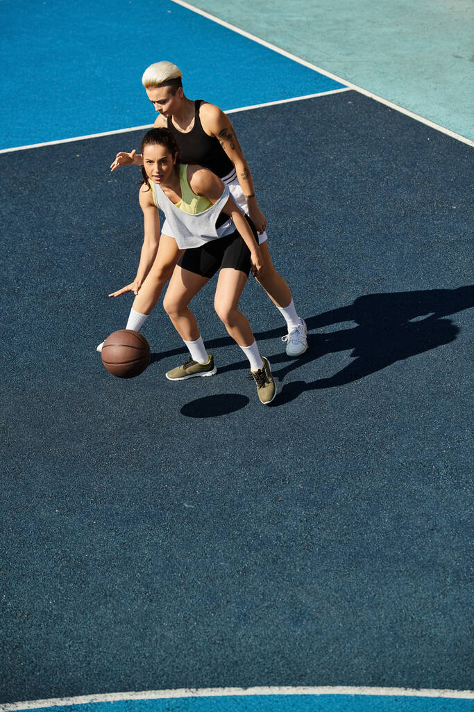 γυναίκες απολαμβάνουν ένα φιλικό παιχνίδι μπάσκετ σε ένα υπαίθριο γήπεδο κάτω από τον καλοκαιρινό ήλιο. - Φωτογραφία, εικόνα