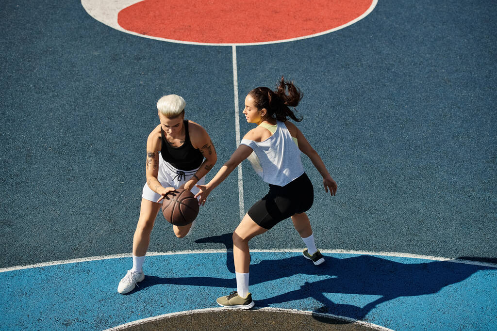 Δύο αθλήτριες στέκονται με αυτοπεποίθηση σε ένα γήπεδο μπάσκετ, έτοιμες να αντιμετωπίσουν κάθε πρόκληση που τους παρουσιάζεται.. - Φωτογραφία, εικόνα