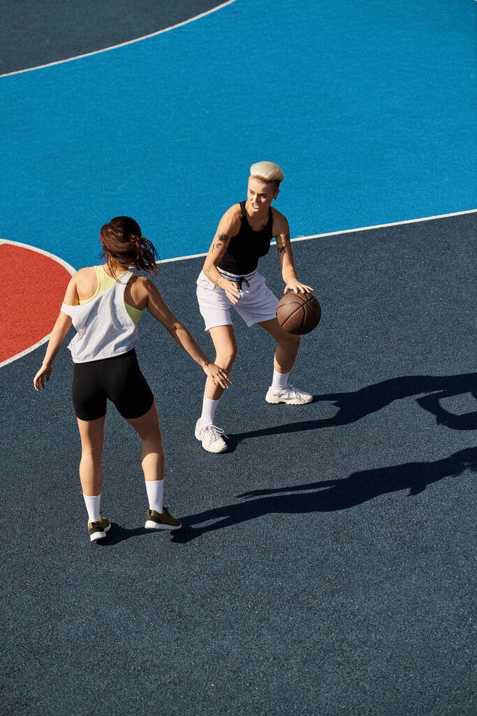 Kaksi nuorta naista seisoo luottavaisin mielin koripallokentän huipulla, ja heillä on voimaa ja tiimityöskentelyä kesäauringon alla.. - Valokuva, kuva