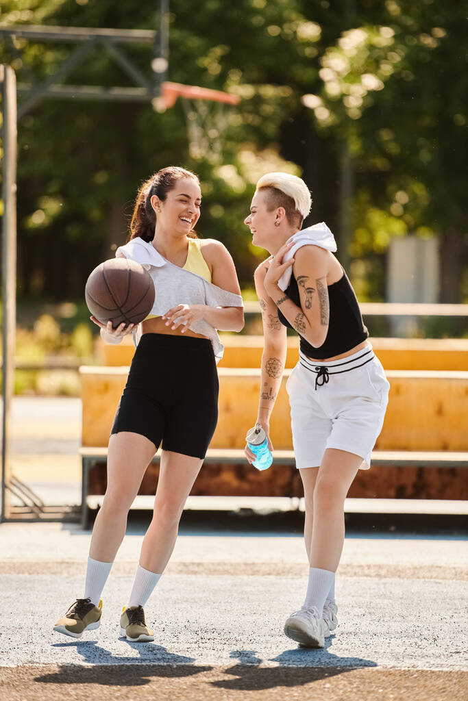 Zwei athletische junge Frauen dribbeln und schießen Körbe auf einem sonnigen Outdoor-Basketballfeld im Sommer. - Foto, Bild