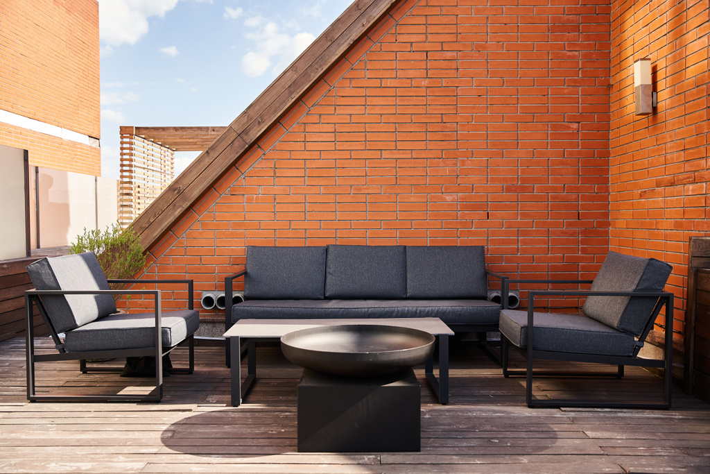 Uma configuração aconchegante de um sofá e cadeiras em um deck de madeira, cercado pela natureza, perfeito para relaxar ou entreter ao ar livre - Foto, Imagem