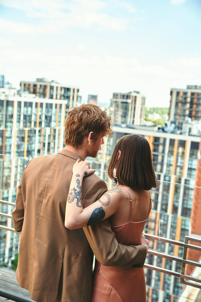 Ένας άντρας και μια γυναίκα στέκονται μαζί σε ένα μπαλκόνι, απολαμβάνοντας τη θέα και ο ένας την παρέα του άλλου σε ένα ήρεμο απόγευμα - Φωτογραφία, εικόνα