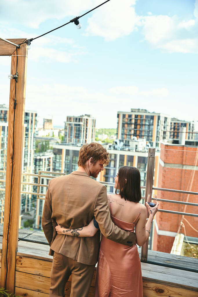 Ein Mann und eine Frau stehen selbstbewusst auf einem Dach und blicken auf das riesige Stadtbild unter ihnen. - Foto, Bild