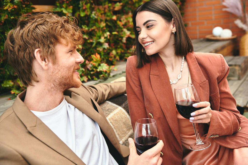 Um homem e uma mulher desfrutando de um copo de vinho juntos em um ambiente íntimo, compartilhando um momento de conexão e proximidade - Foto, Imagem