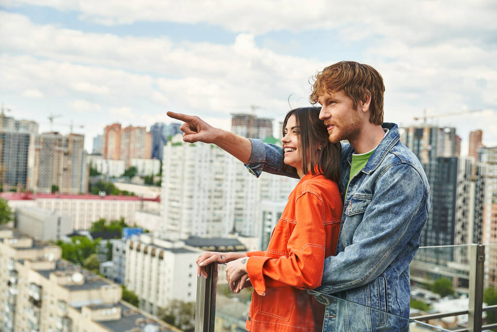 Um homem e uma mulher confiantes no telhado de um edifício, olhando para o horizonte da cidade com temor e determinação - Foto, Imagem
