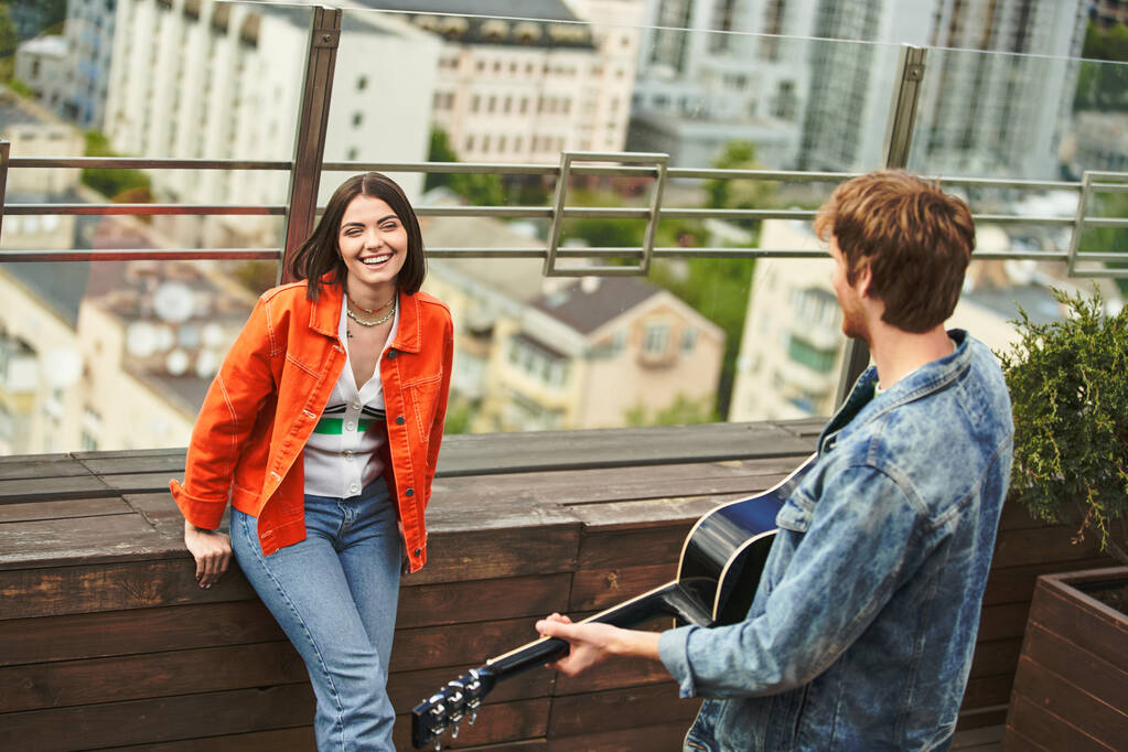 Egy nő gitárt tart, miközben egy férfi mellett áll egy harmonikus és zenei színtéren. - Fotó, kép