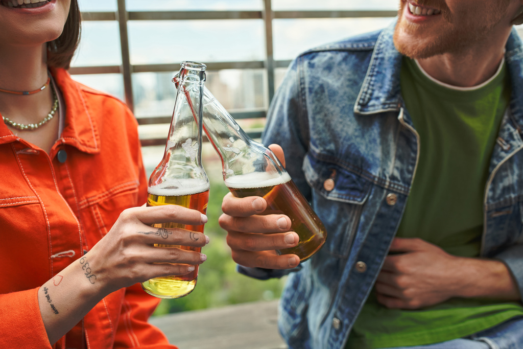 Un hombre y una mujer están disfrutando de la compañía de los demás, compartiendo un momento sobre cervezas en un ambiente acogedor - Foto, imagen