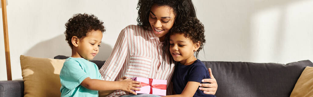 hermosa alegre afroamericana mujer recibiendo regalo de sus adorables hijos en el día de la madre - Foto, Imagen