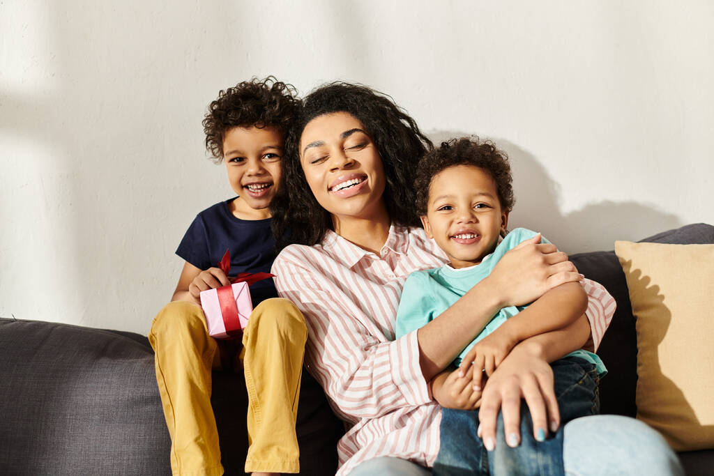 alegre mujer afroamericana posando con adorables hijos pequeños y mirando a la cámara, Día de las Madres - Foto, Imagen