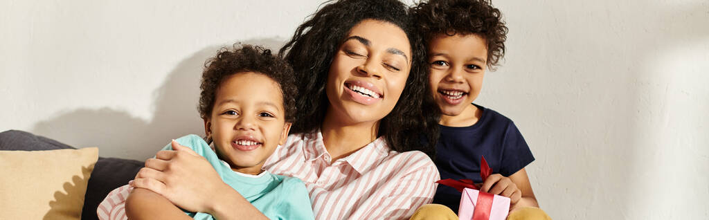 wesoła Afroamerykanka uśmiecha się do kamery ze swoimi małymi, słodkimi synami, Dzień Matki, transparent - Zdjęcie, obraz