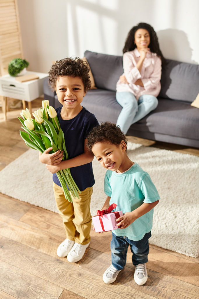 se concentrer sur les enfants afro-américains joyeux avec des tulipes et des cadeaux posant près de leur mère floue, Fête des mères - Photo, image