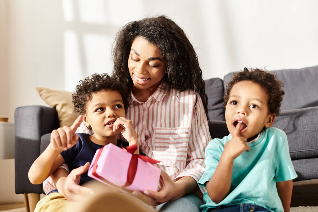 весела афроамериканська сім'я з трьох позує разом і тримає подарунок, день матері - Фото, зображення