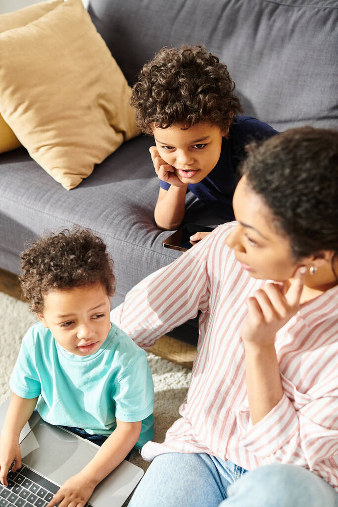 bien parecido afroamericano madre teniendo gran tiempo con sus adorables hijos pequeños en sala de estar - Foto, imagen