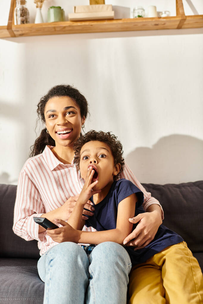 joyous african american mother and her shocked little son watching interesting movie at home - Photo, Image