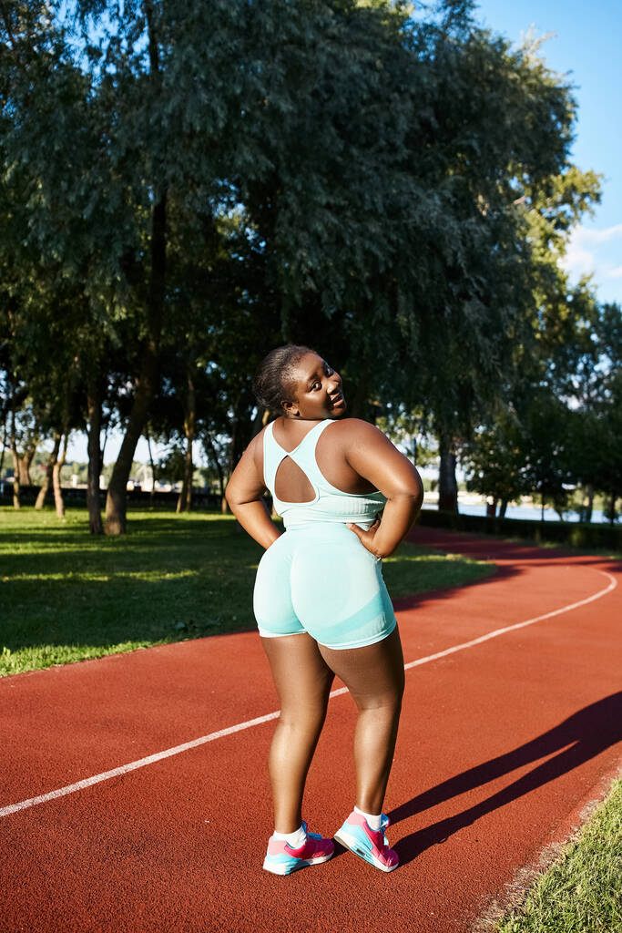 Африканська американка в спортивному одязі впевнено стоїть на тенісному корті з руками на стегнах. - Фото, зображення