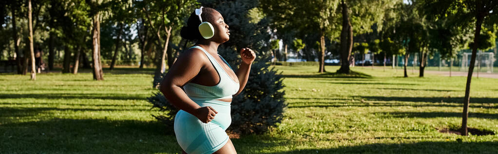 Una mujer afroamericana en ropa deportiva, corre graciosamente en una cancha en un entorno al aire libre. - Foto, imagen