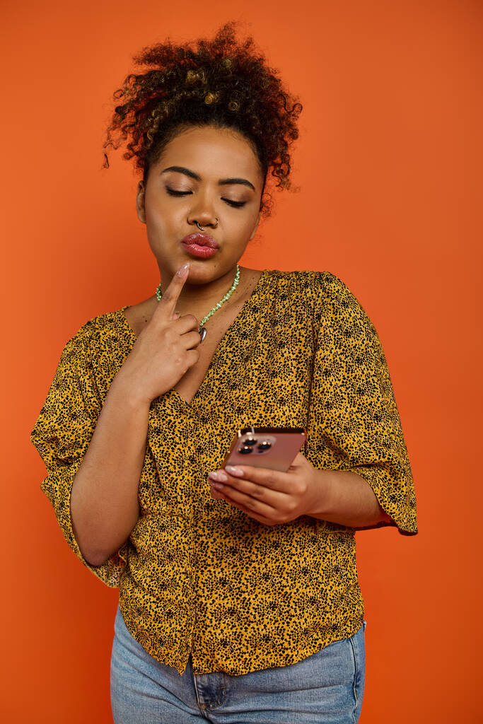Красивая афроамериканка в стильной одежде смотрит на свой мобильный телефон. - Фото, изображение
