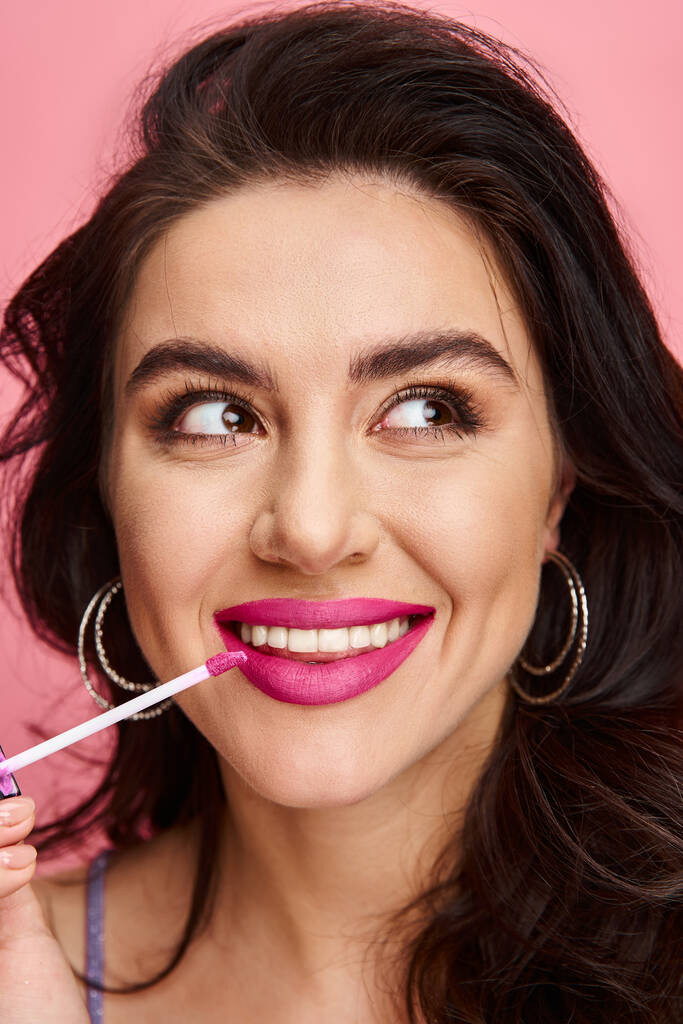 vrouw showcasing een schitterende glimlach met levendige roze lippenstift op haar lippen. - Foto, afbeelding