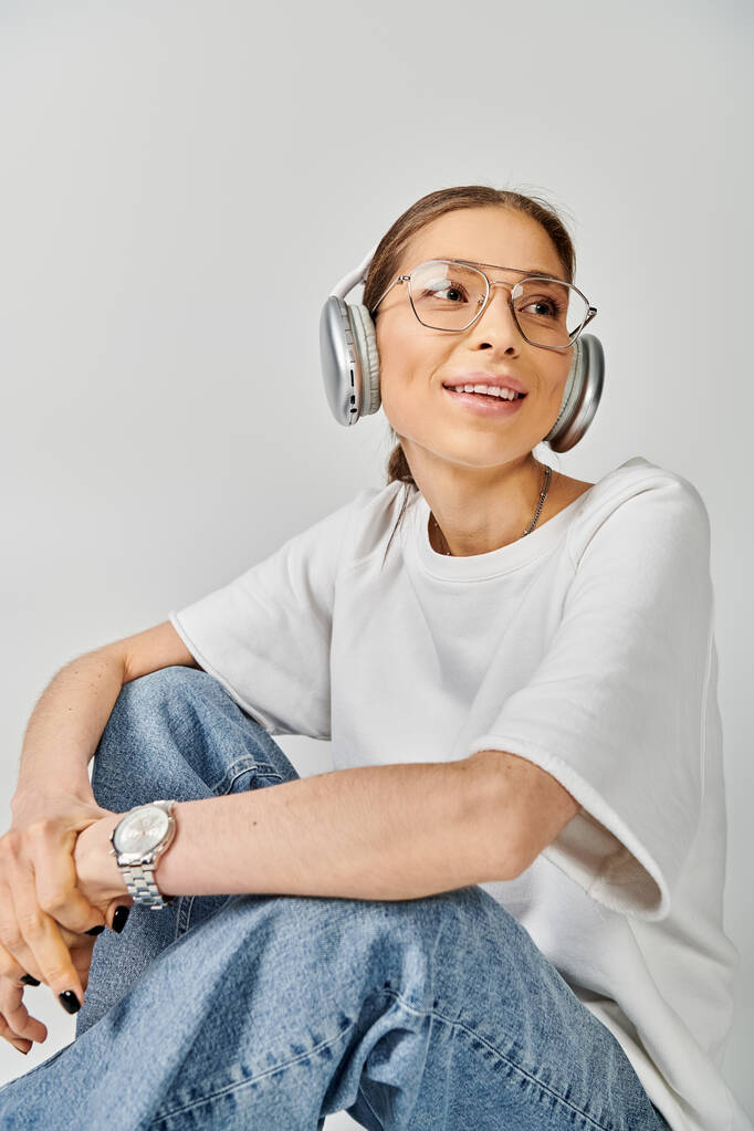 Egy fiatal nő fehér pólóban és szemüvegben fülhallgatót visel, elveszett a zenében.. - Fotó, kép