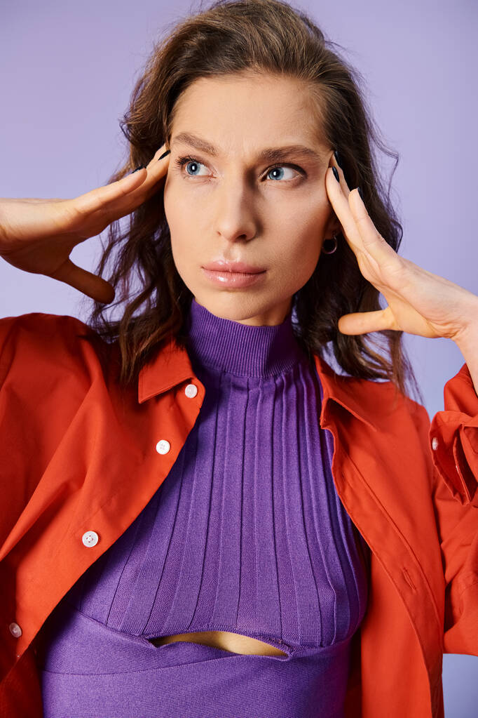 Una giovane donna elegante si distingue in un top viola e una giacca rossa vibrante su uno sfondo viola. - Foto, immagini