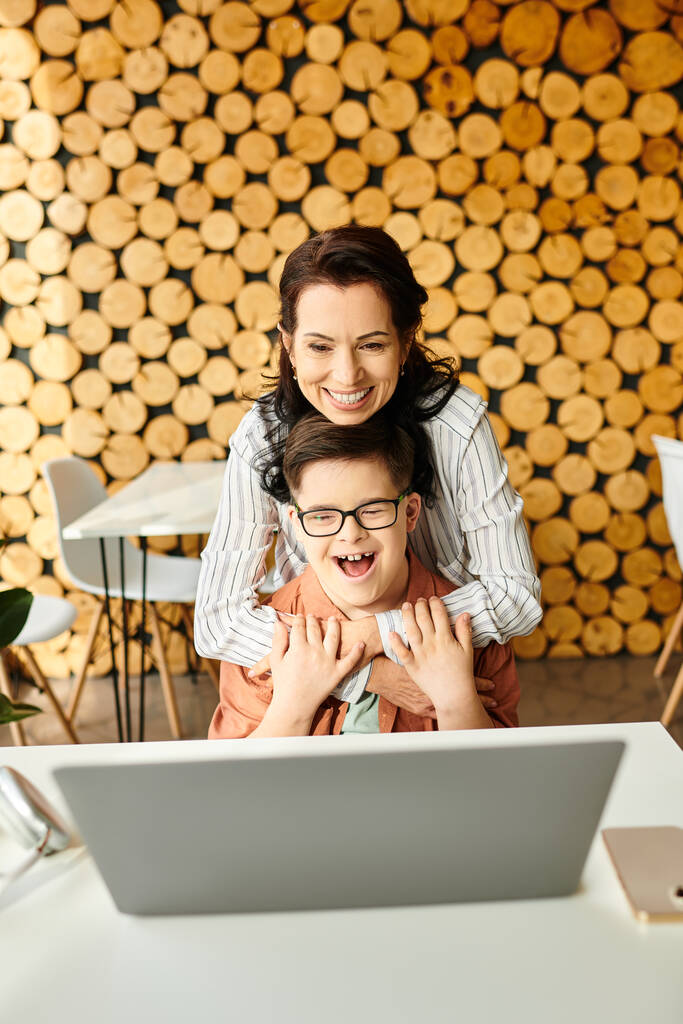 piękna radosna matka patrząc na laptopa z jej inclusive cute syn z zespołem Downa w kawiarni - Zdjęcie, obraz