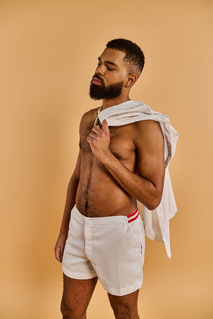 Un hombre con la barba llena está sin camisa en un entorno tranquilo, conectándose con la naturaleza a través de su pecho desnudo. - Foto, Imagen