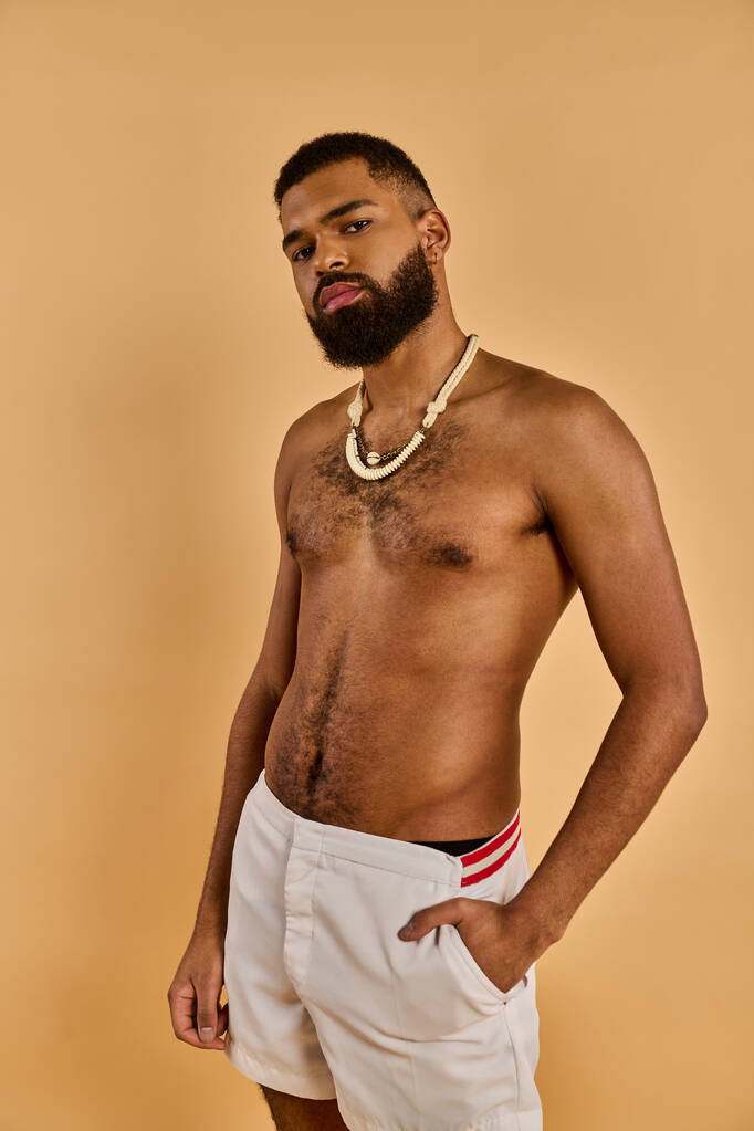 A man with a full beard stands confidently, sporting white shorts. His beard adds a rugged touch to his relaxed and casual outfit. - Photo, Image