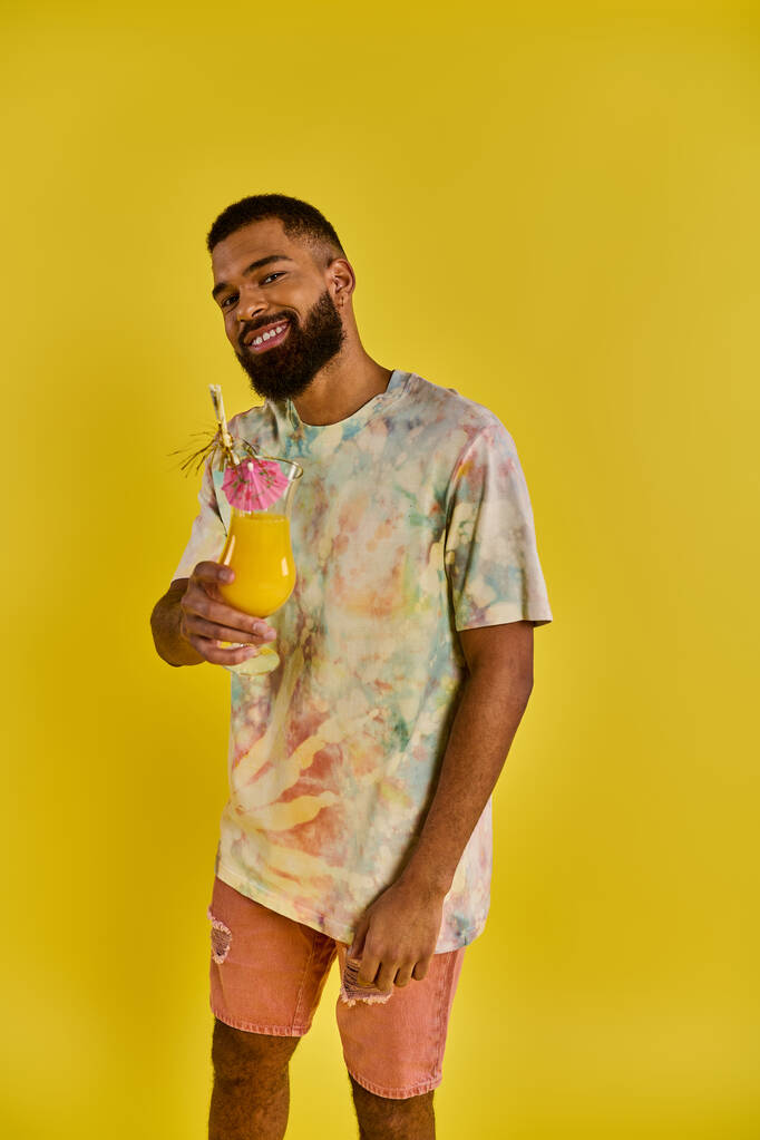 Stylowy mężczyzna w krawatowej koszuli, trzymający napój, dodający odrobinę koloru scenie z jego żywym strojem. - Zdjęcie, obraz