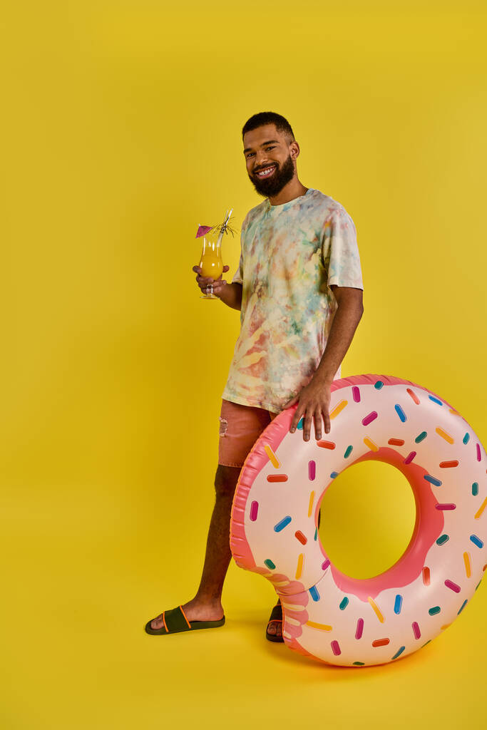 Um homem fica admirado ao lado de um donut gigante, anão pelo seu enorme tamanho. O donut é colorido e tentador, implorando para ser comido. - Foto, Imagem