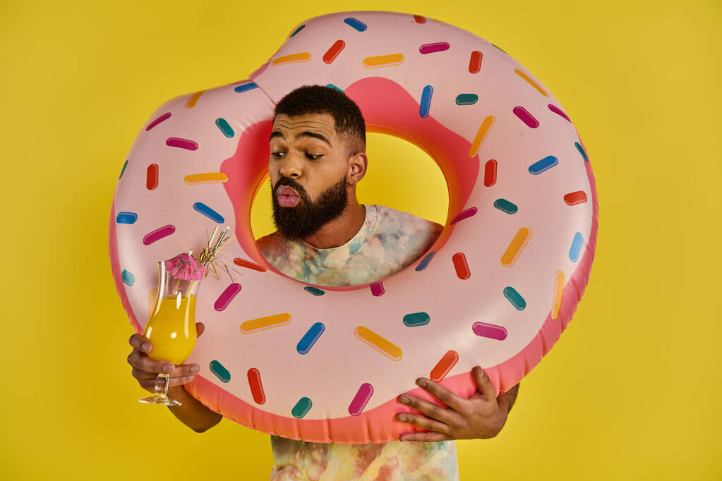 Een man houdt een gigantische donut in de ene hand en een glas sinaasappelsap in de andere, met een heerlijk ontbijt traktatie. - Foto, afbeelding