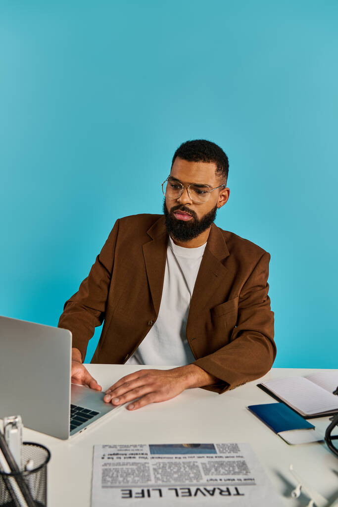Ein Mann sitzt an einem Schreibtisch, in seinen Laptop-Bildschirm vertieft. Seine Finger tanzen über die Tastatur und schaffen digitale Meisterwerke. - Foto, Bild