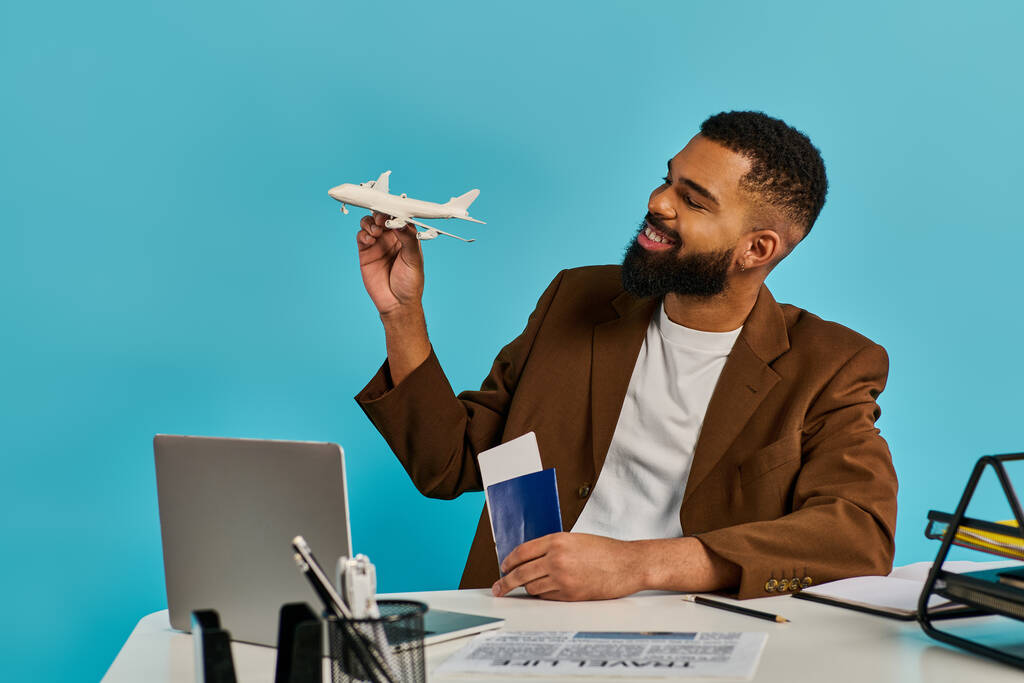 Egy férfi ül egy asztalnál, kezében egy repülőgép modellel, mélyen elgondolkodva. Alaposan megvizsgálja és dolgozik a kis repülőgépek bonyolult részletein.. - Fotó, kép