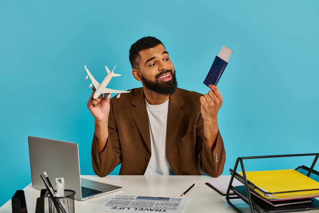 Un homme est assis à un bureau, tenant un passeport et des billets d'avion, symbolisant l'excitation et l'anticipation des aventures de voyage à venir. - Photo, image