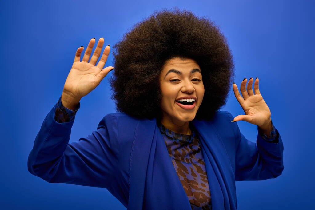 Elegante mujer afroamericana con cabello rizado haciendo una cara divertida en el vibrante telón de fondo. - Foto, imagen