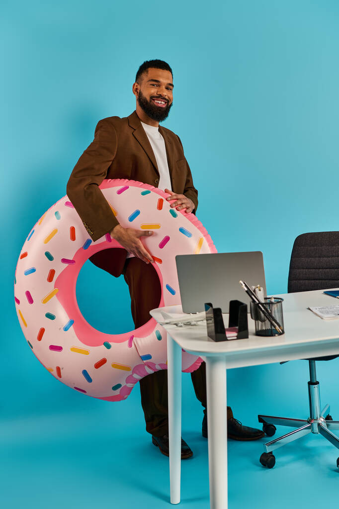 Un hombre se sienta en un escritorio, mirando una enorme dona frente a él. El donut es más grande que la vida, atractivo y surrealista. - Foto, imagen