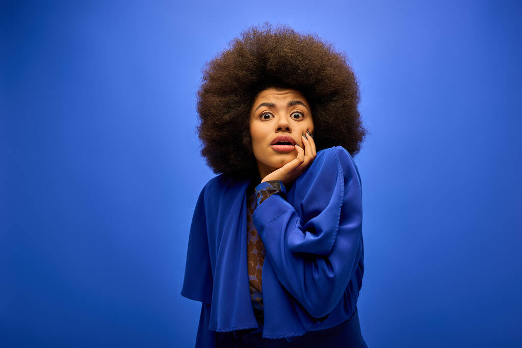 Eine stylische Afroamerikanerin mit lockigem Haar posiert in trendiger Kleidung vor einer lebendigen Kulisse. - Foto, Bild