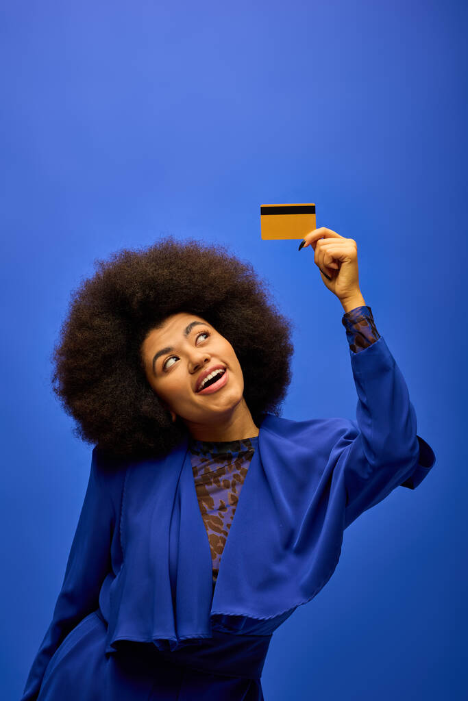 Elegante mujer afroamericana con el pelo rizado sosteniendo una tarjeta de crédito. - Foto, imagen