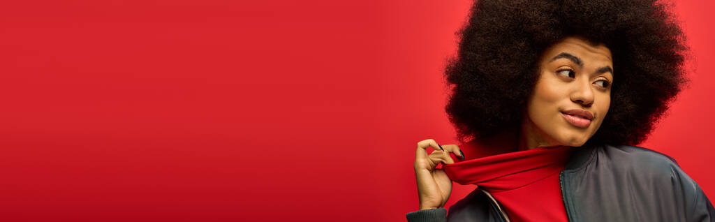 Uma mulher com penteado encaracolado mantém um lenço vermelho vibrante em uma pose na moda. - Foto, Imagem