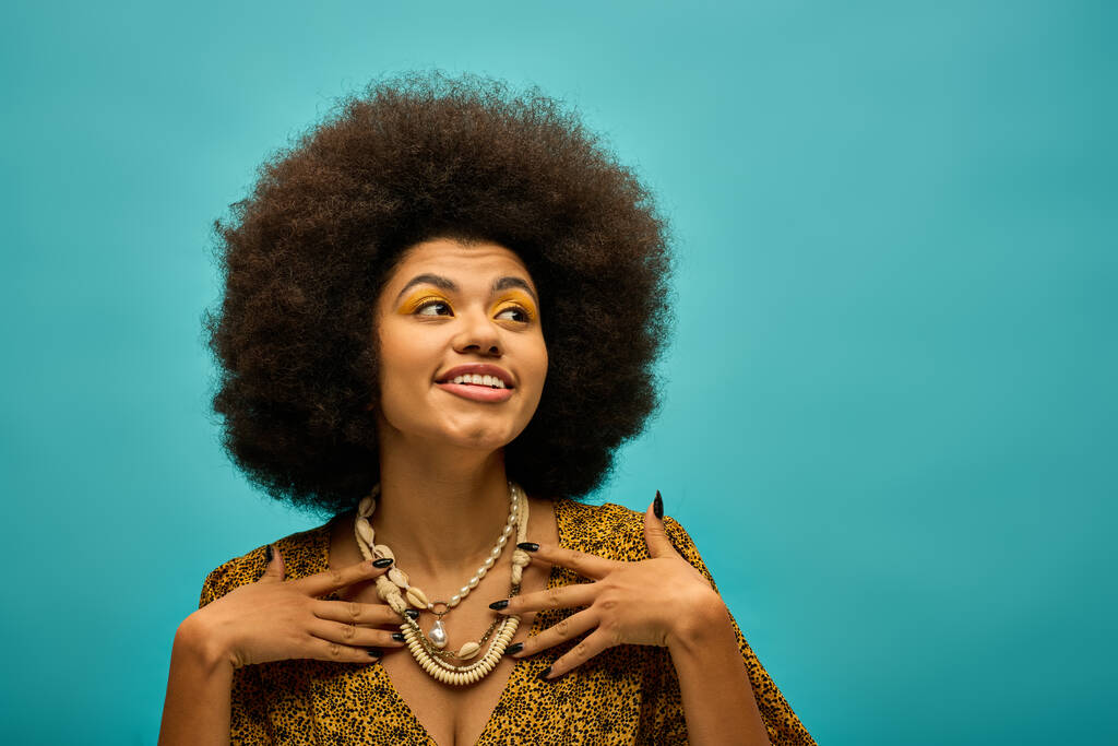 Una mujer afroamericana de moda con un afro voluminoso posa en un atuendo de moda sobre un vibrante telón de fondo. - Foto, imagen