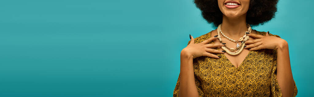 Kıvırcık saçlı, canlı mavi arka planda poz veren şık Afrikalı Amerikalı kadın.. - Fotoğraf, Görsel