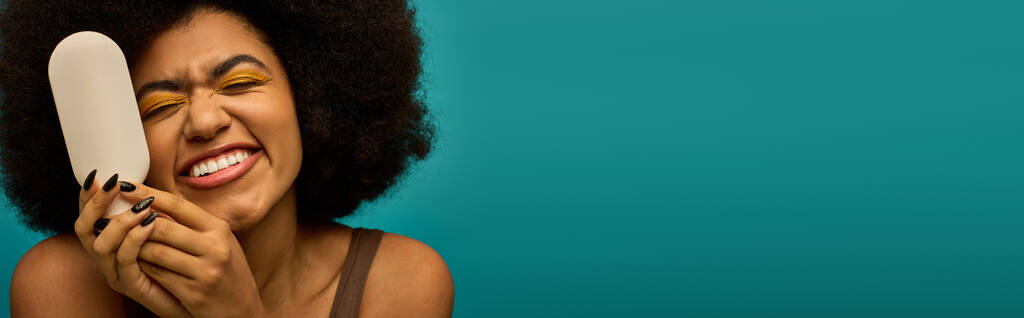 Stilvolle Afroamerikanerin mit Pinsel vor lebendigem Hintergrund. - Foto, Bild