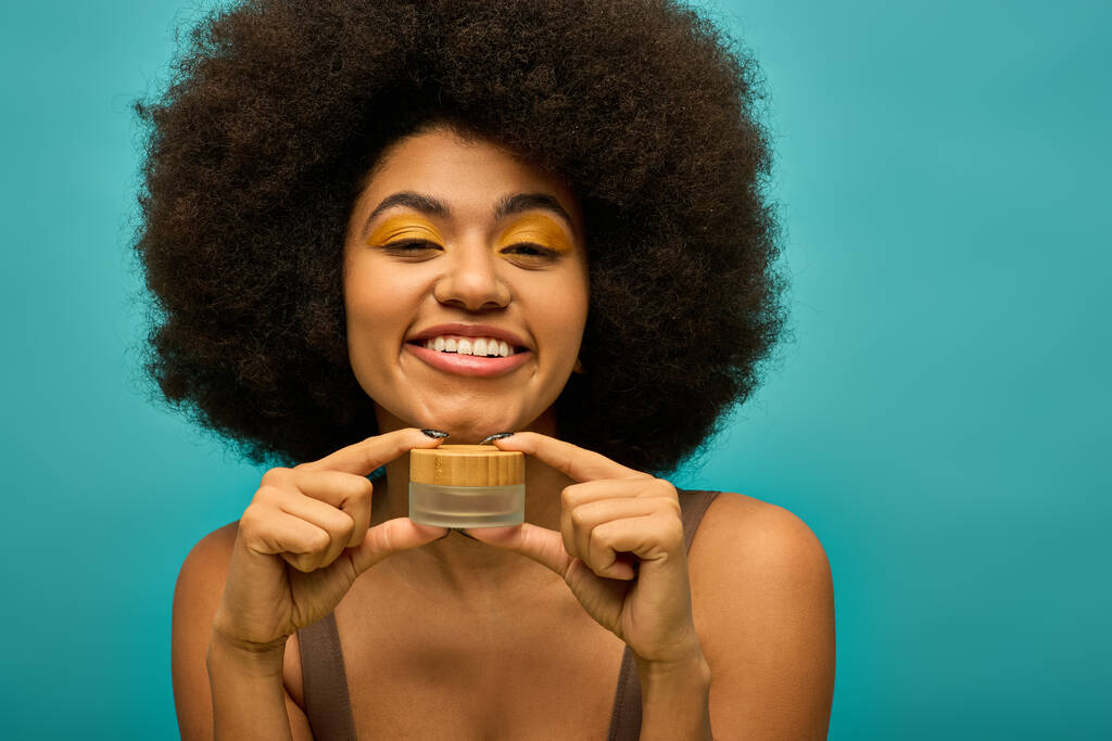 Trendy Afro-Amerikaanse vrouw met krullend haar holding crème. - Foto, afbeelding