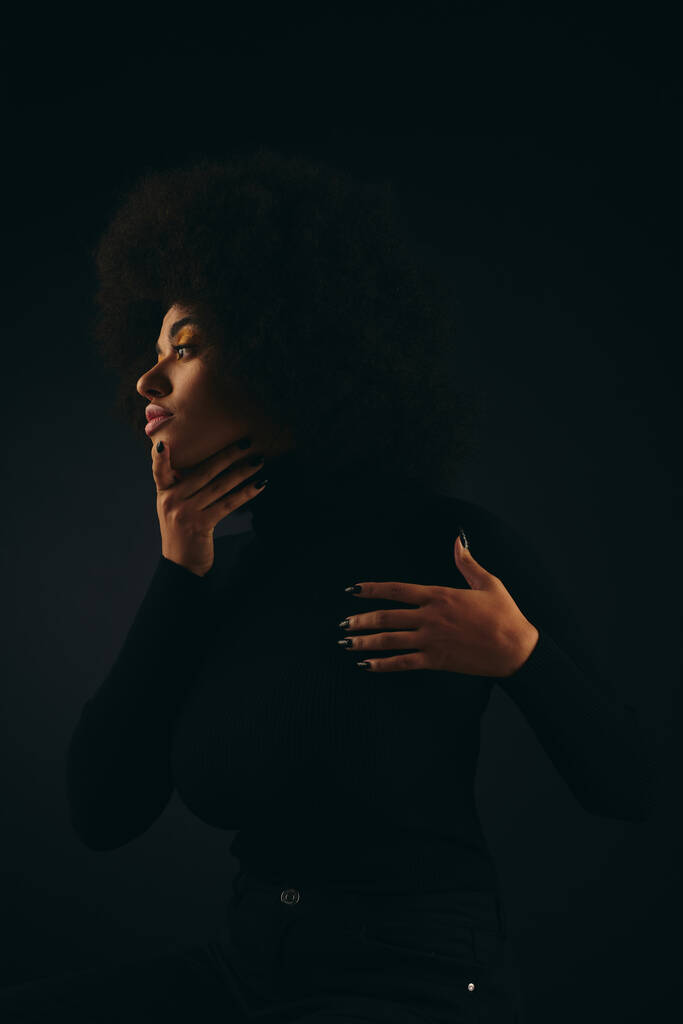 Elegante mujer afroamericana con las manos en el pecho en traje de moda contra el telón de fondo vibrante. - Foto, Imagen
