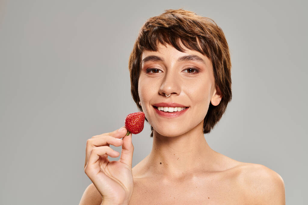 Una joven delicadamente sosteniendo una fresa en su mano. - Foto, imagen
