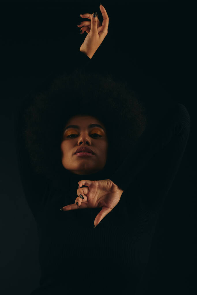 Κομψή Αφρο-Αμερικανίδα γυναίκα με το χέρι σηκωμένο στον αέρα σε ένα ζωντανό σκηνικό. - Φωτογραφία, εικόνα