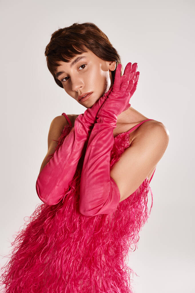 Una giovane donna alla moda in un abito rosa e guanti in posa elegantemente. - Foto, immagini