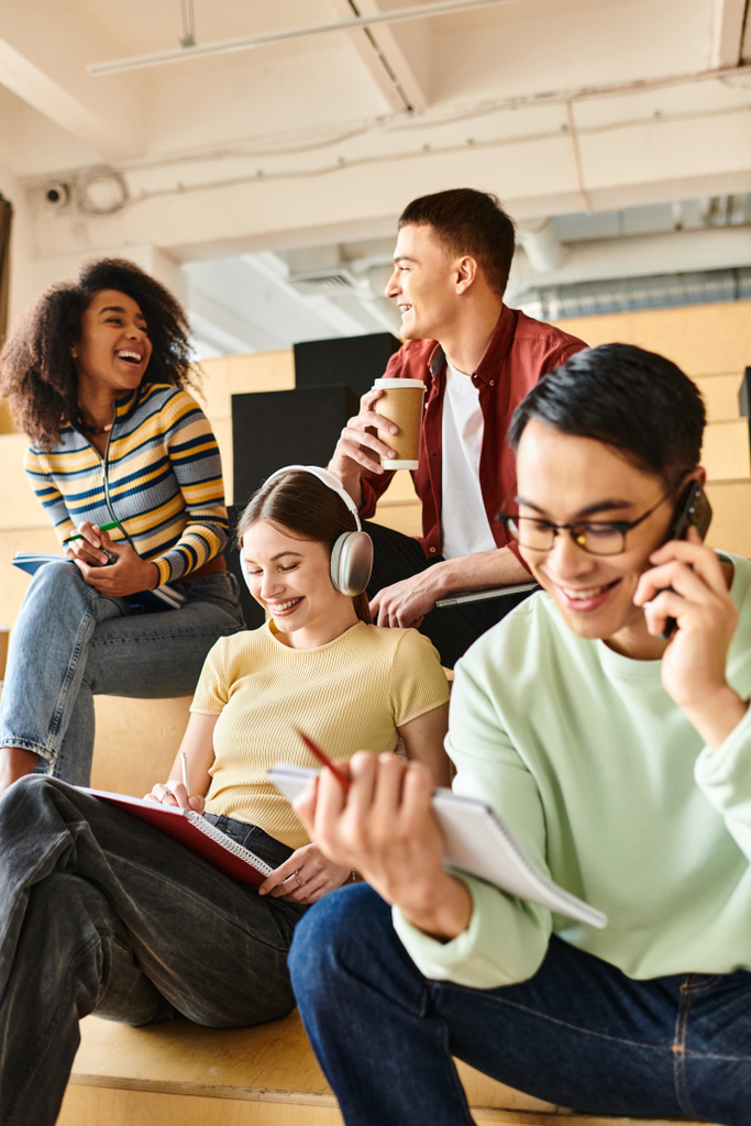 Різноманітна група студентів, зацікавлених у розмовах мобільних телефонів, сидячи на кроках - Фото, зображення