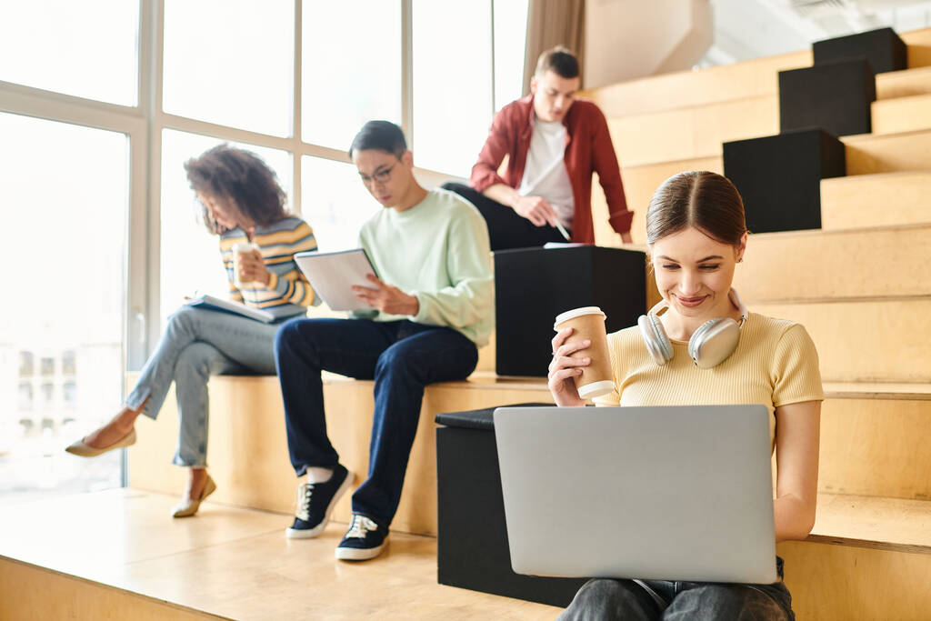 Multikulturelle Gruppe junger Leute, die auf Treppen sitzen, sich auf Laptops konzentrieren und sich mit digitalem Lernen beschäftigen - Foto, Bild