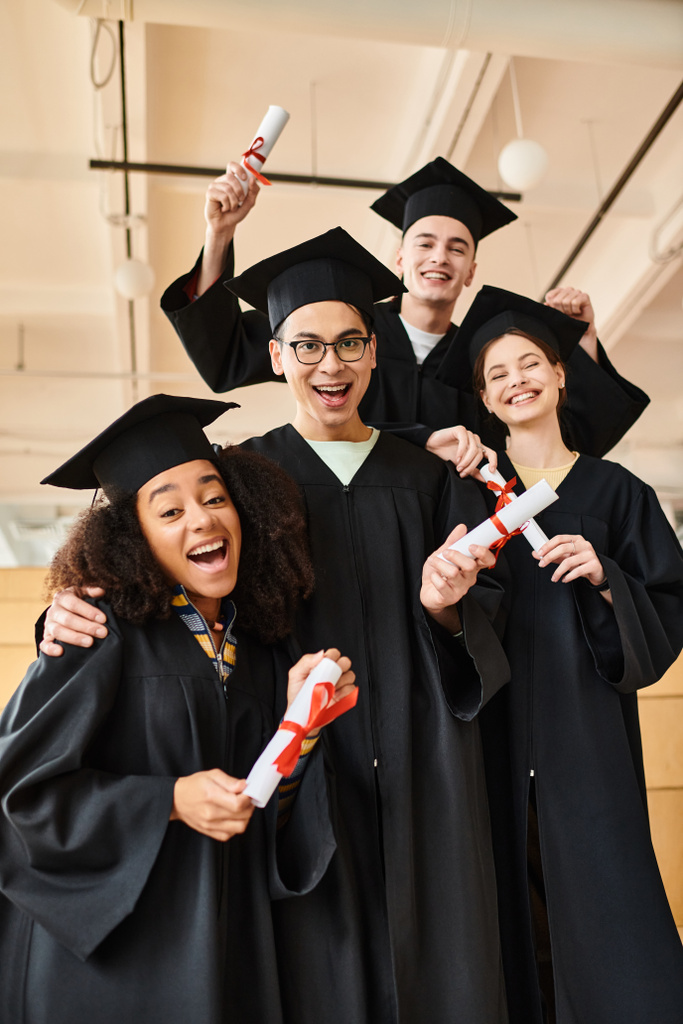 Diákok sokszínű csoportja ballagási köpenyben és akadémiai sapkában, akik egy képre mosolyognak, hogy megemlékezzenek oktatási mérföldköveikről.. - Fotó, kép