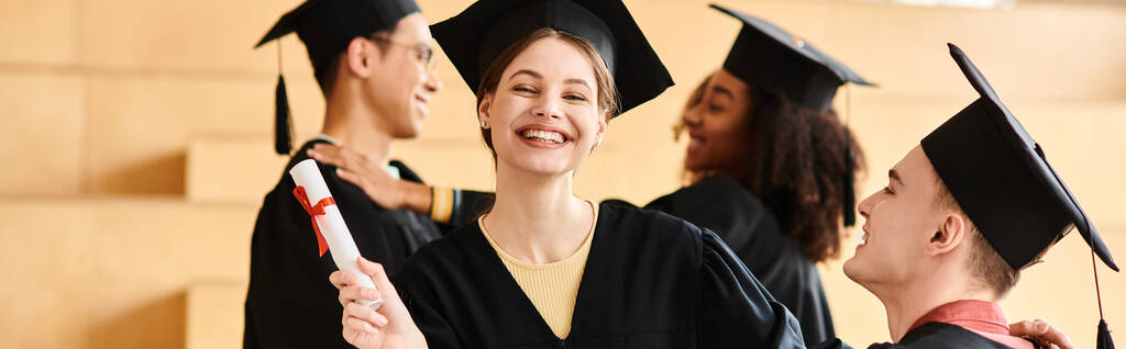 Grupa szczęśliwych studentów w czapkach i sukniach absolwentów świętujących swoje osiągnięcia akademickie na ceremonii uniwersyteckiej. - Zdjęcie, obraz